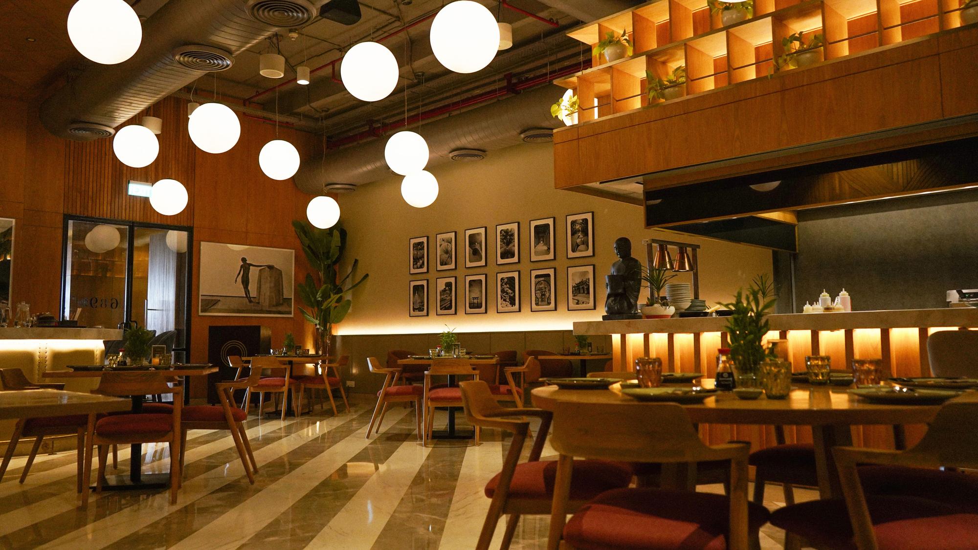 A dining room lit by globe pendants, set before service